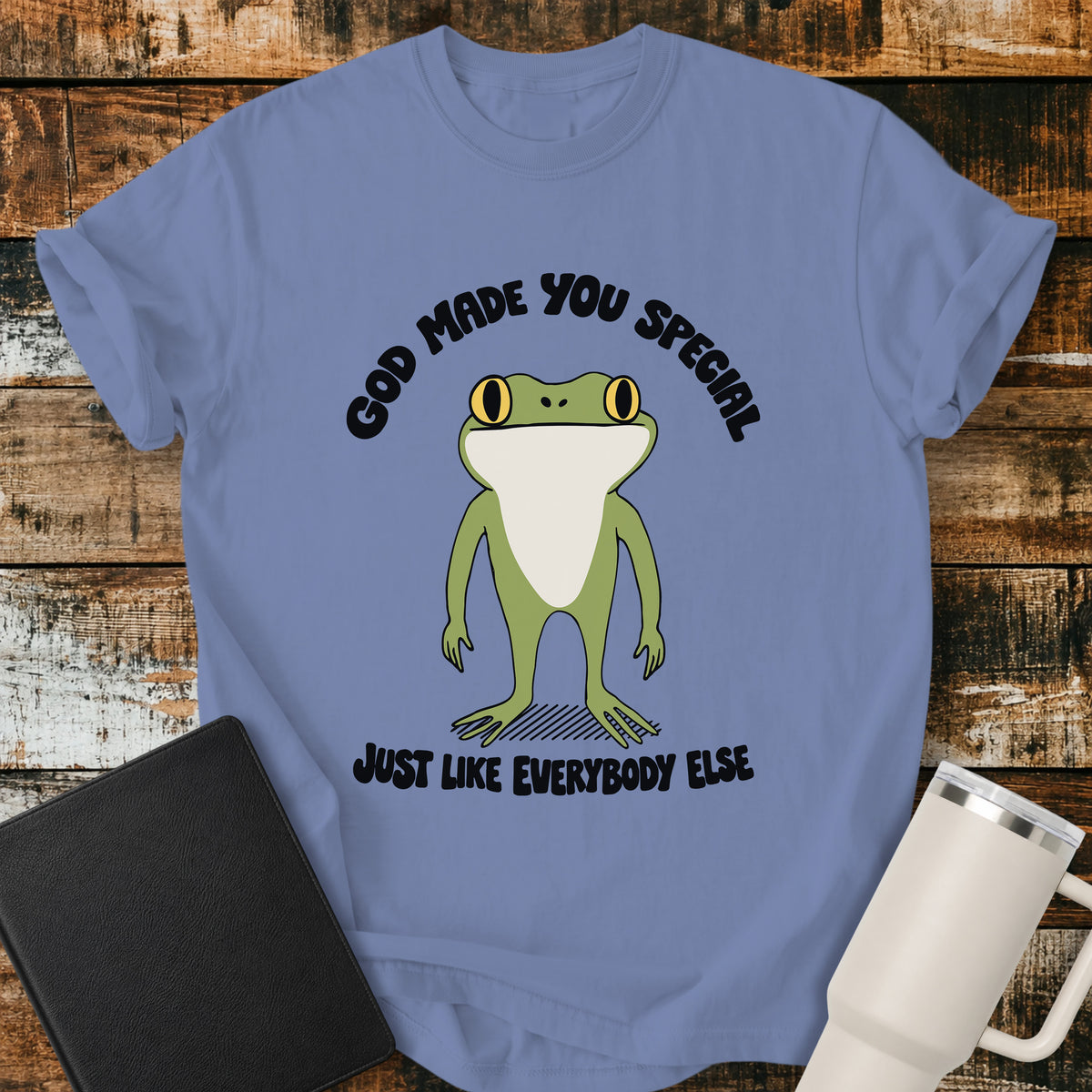 washed denim blue Christian T-shirt featuring a retro frog with the words “God Made You Special Just Like Everybody Else” in black lettering.