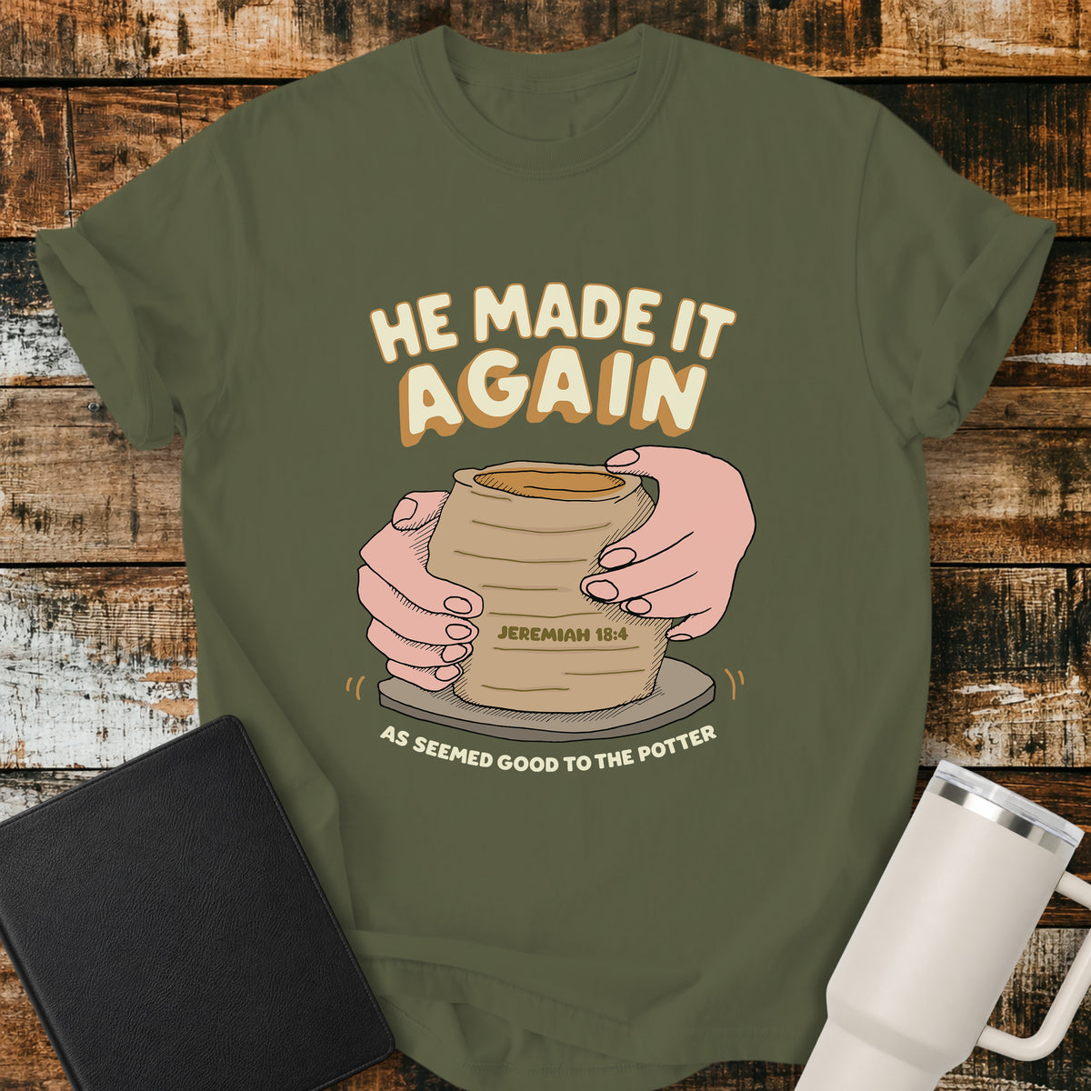hemp green Christian t-shirt featuring hands shaping a clay vessel on a potter’s wheel, with the phrase “He Made It Again,” Jeremiah 18:4, and “As Seemed Good to the Potter.” A retro-inspired biblical design illustrating God as the Potter.