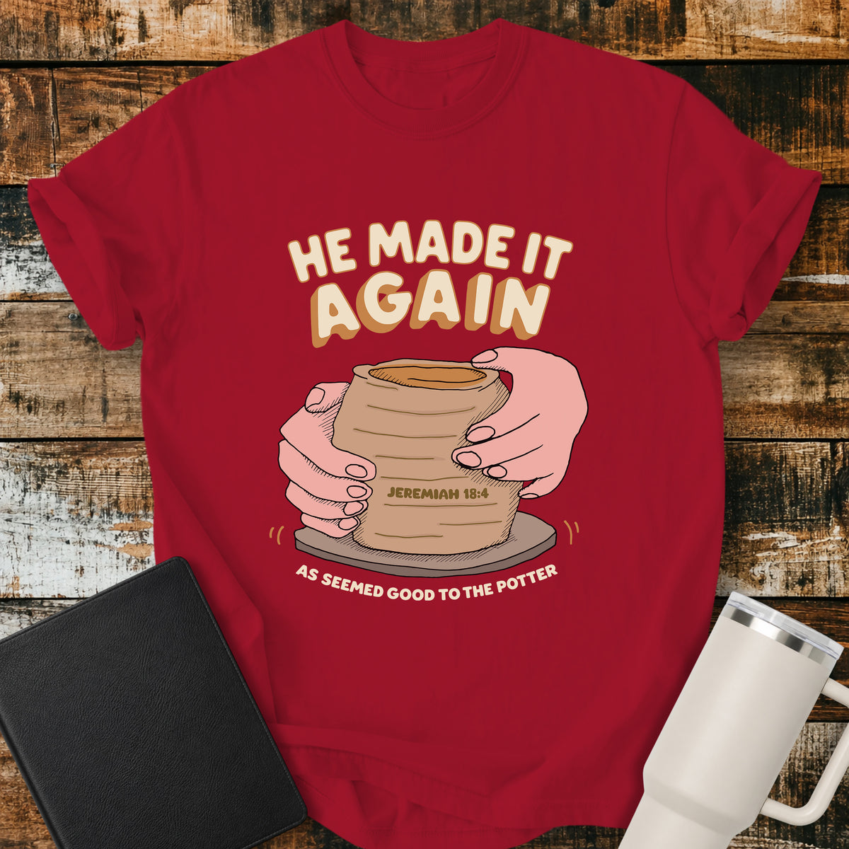 red Christian t-shirt featuring hands shaping a clay vessel on a potter’s wheel, with the phrase “He Made It Again,” Jeremiah 18:4, and “As Seemed Good to the Potter.” A retro-inspired biblical design illustrating God as the Potter.
