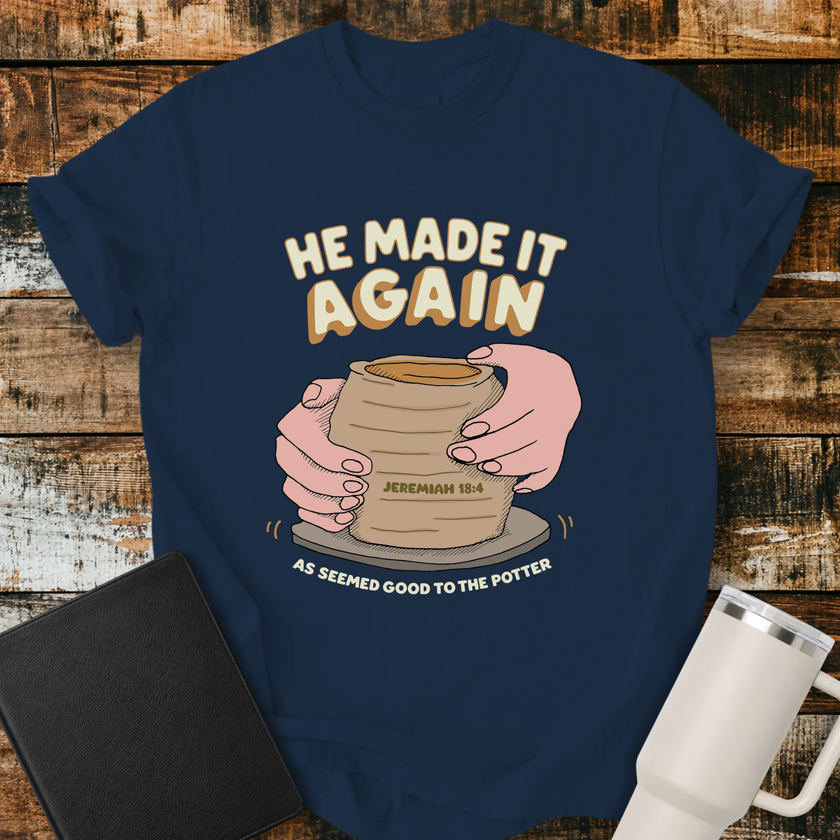 True navy Christian t-shirt featuring hands shaping a clay vessel on a potter’s wheel, with the phrase “He Made It Again,” Jeremiah 18:4, and “As Seemed Good to the Potter.” A retro-inspired biblical design illustrating God as the Potter.