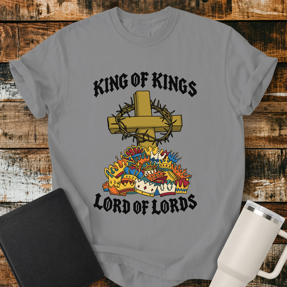 Grey Christian T-shirt featuring a golden cross wrapped in a crown of thorns above a colorful collection of crowns, framed by the bold declaration “KING OF KINGS” and “LORD OF LORDS.”