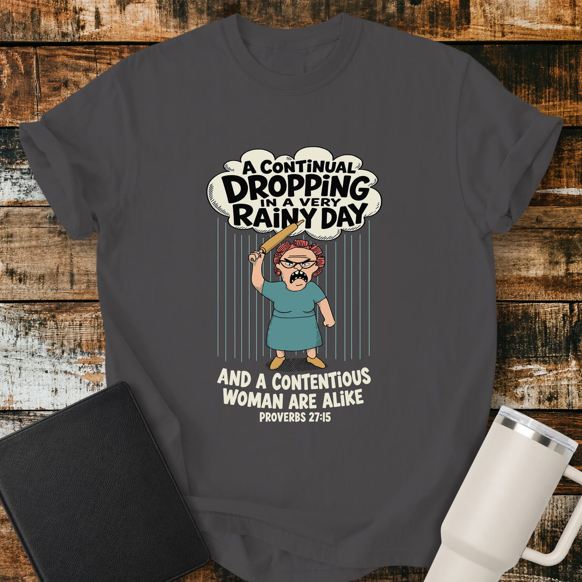 graphite Christian t-shirt featuring a humorous illustration inspired by Proverbs 27:15, with the verse “A continual dropping in a very rainy day and a contentious woman are alike.”