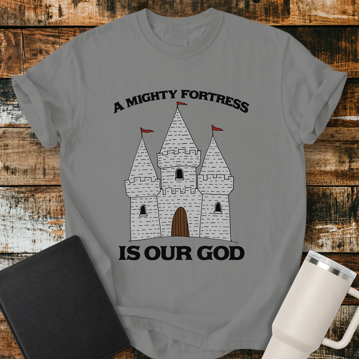 granite grey Christian t-shirt featuring a hand-drawn castle illustration with bold vintage lettering reading “A Mighty Fortress Is Our God.”