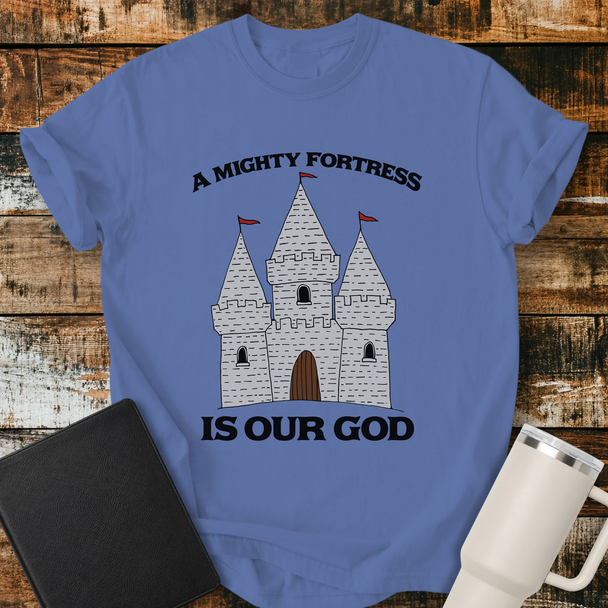mystic blue Christian t-shirt featuring a hand-drawn castle illustration with bold vintage lettering reading “A Mighty Fortress Is Our God.”