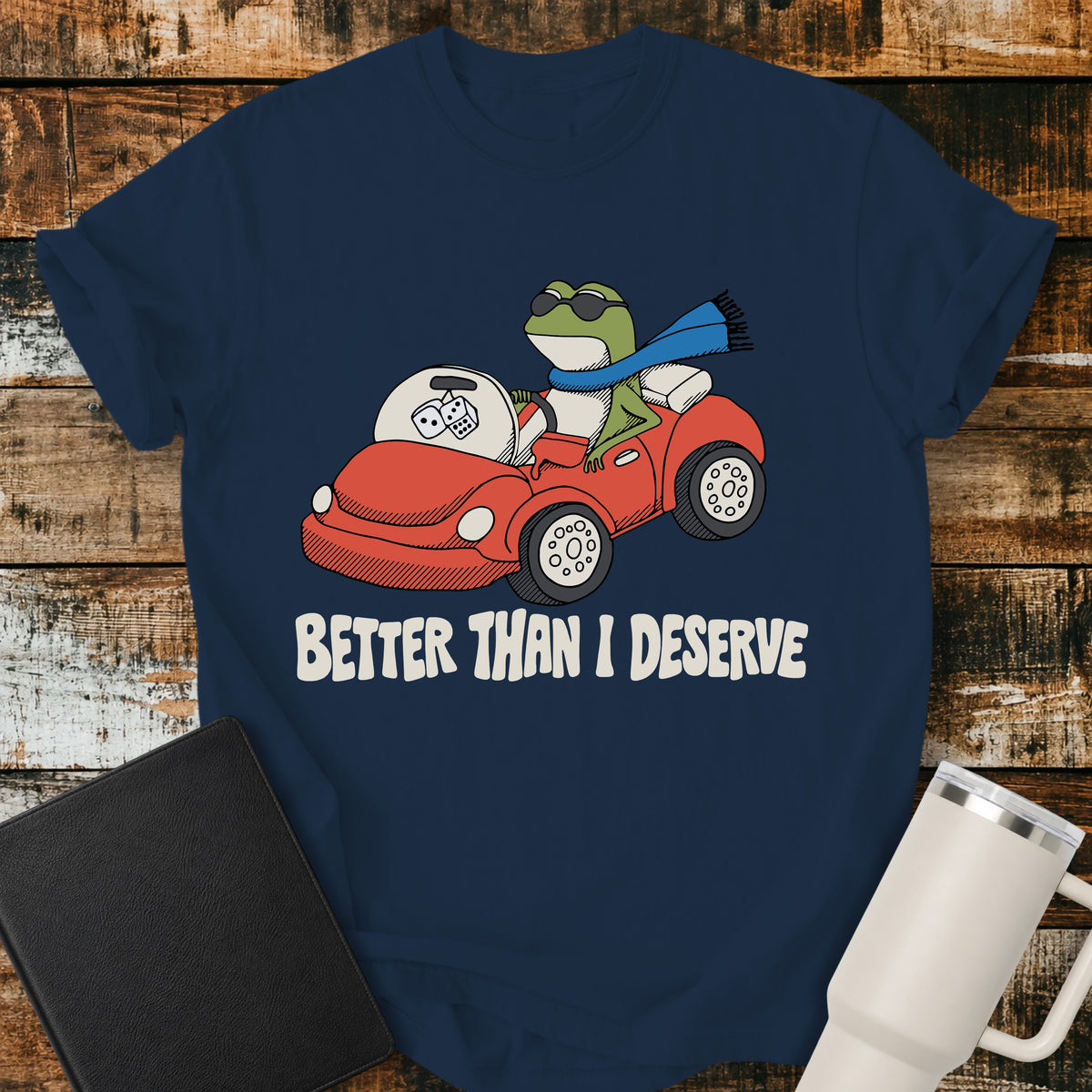 true navy blue Christian T-shirt featuring a frog driving a red convertible with the words “Better Than I Deserve” in cream retro lettering.