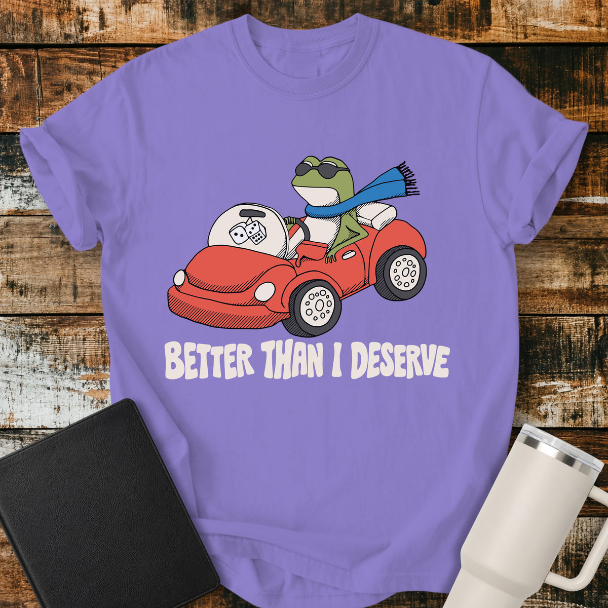 violet Christian T-shirt featuring a frog driving a red convertible with the words “Better Than I Deserve” in cream retro lettering.