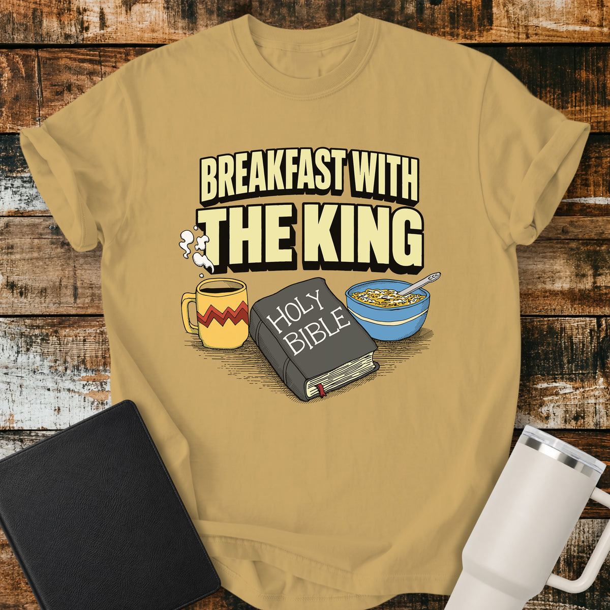 mustard Christian t-shirt featuring the phrase “Breakfast With the King” above a retro illustrated Holy Bible, steaming coffee mug, and bowl of cereal. A colorful vintage-inspired faith design with a fun breakfast theme.