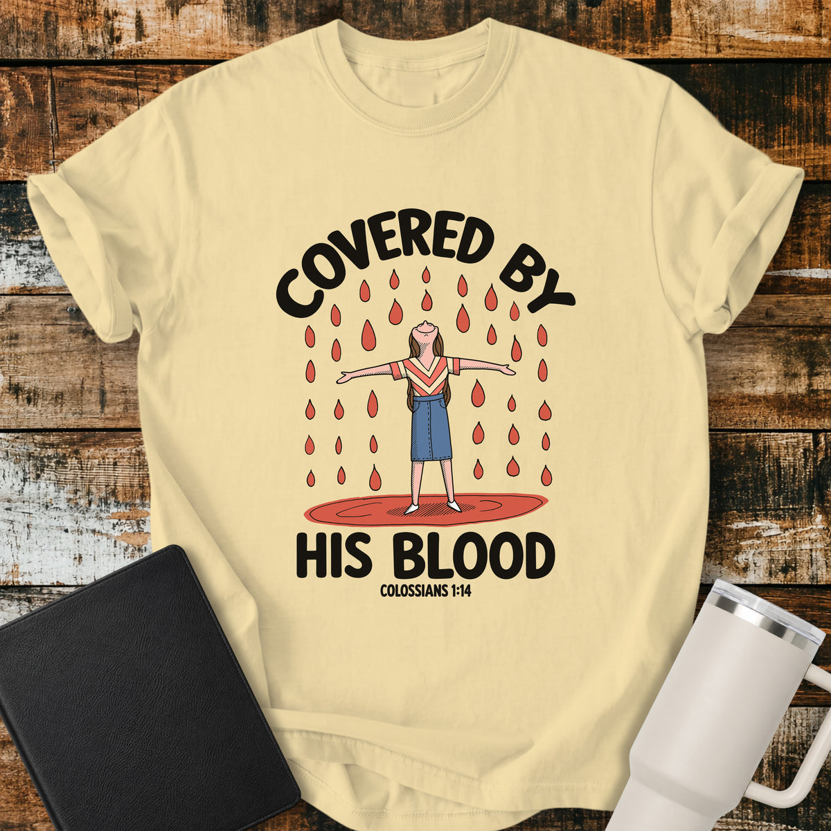 banana yellow Christian t-shirt featuring a woman standing beneath falling drops with the bold message “Covered By His Blood,” inspired by Colossians 1:14.