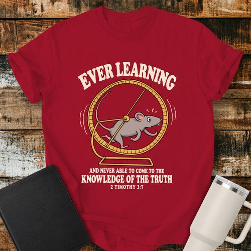 red Christian t-shirt featuring a humorous mouse running endlessly on an exercise wheel, with bold vintage lettering reading “Ever Learning and Never Able to Come to the Knowledge of the Truth” and 2 Timothy 3:7.