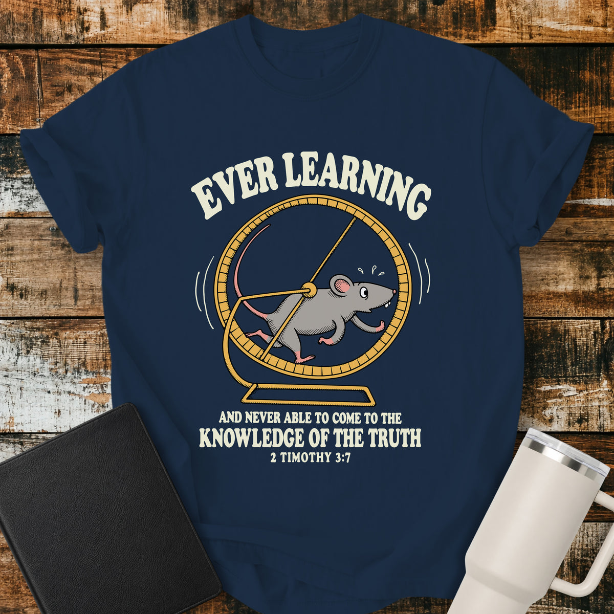 True navy Christian t-shirt featuring a humorous mouse running endlessly on an exercise wheel, with bold vintage lettering reading “Ever Learning and Never Able to Come to the Knowledge of the Truth” and 2 Timothy 3:7.