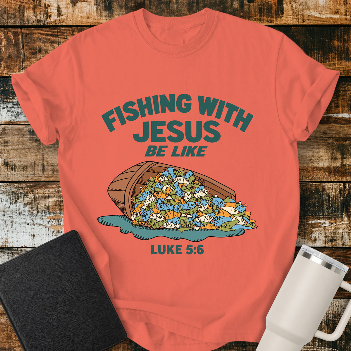 bright salmon Christian t-shirt featuring a humorous overflowing catch of fish spilling from a boat, with bold retro text reading “Fishing With Jesus Be Like” and Luke 5:6.