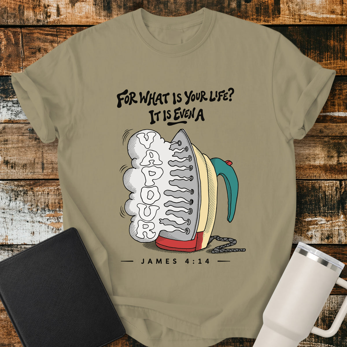 Khaki flat-lay t-shirt mockup featuring a colorful vintage-style steam iron releasing a large cloud of steam shaped into the word "VAPOUR." Above the illustration, stylized lettering reads, "FOR WHAT IS YOUR LIFE? IT IS EVEN A," with the Bible reference "JAMES 4:14" below. The faith-inspired design is displayed on a rustic wood plank background alongside a black leather Bible and a white insulated travel mug.