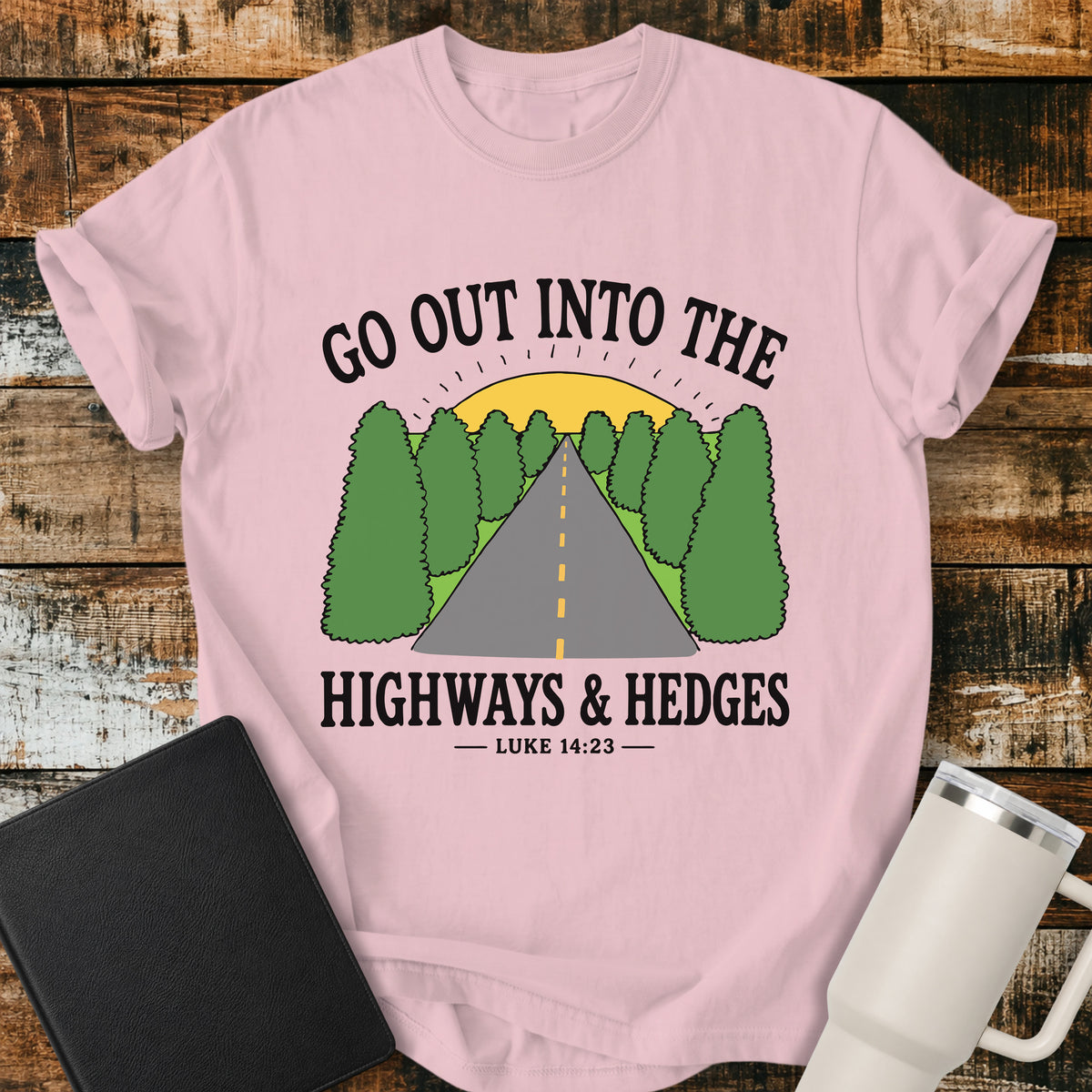 blossom pink Christian t-shirt featuring a retro highway stretching through green hedges toward a sunrise, with the message “Go Out Into the Highways & Hedges” and the scripture reference Luke 14:23.