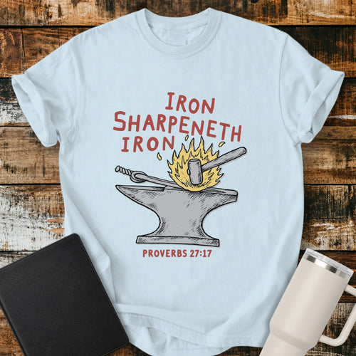 chambray blue Christian T-shirt featuring an anvil, hammer, and fire with the words “Iron Sharpeneth Iron” and “Proverbs 27:17.”