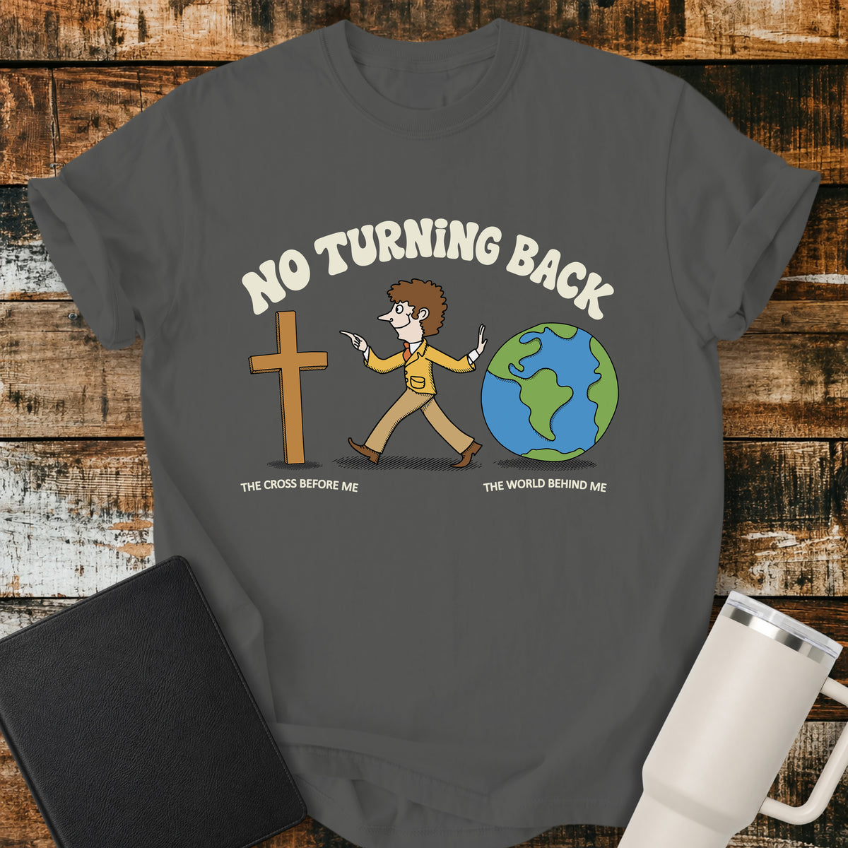 pepper grey Christian t-shirt featuring a retro illustration of a man walking toward the cross and leaving the world behind, with the message “No Turning Back” and the phrases “The Cross Before Me” and “The World Behind Me.”