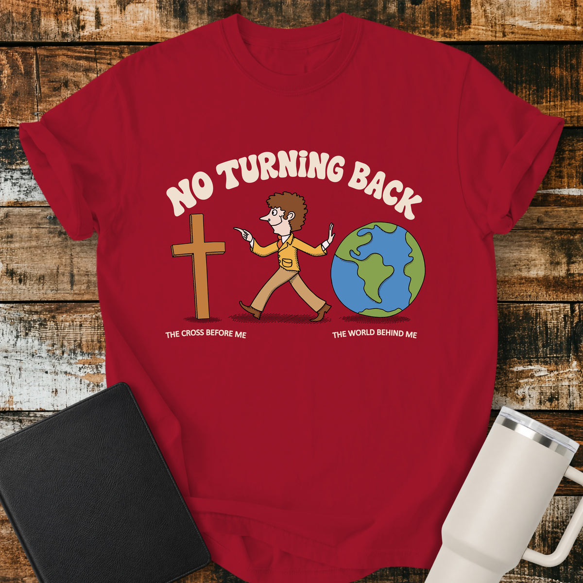Red Christian t-shirt featuring a retro illustration of a man walking toward the cross and leaving the world behind, with the message “No Turning Back” and the phrases “The Cross Before Me” and “The World Behind Me.”