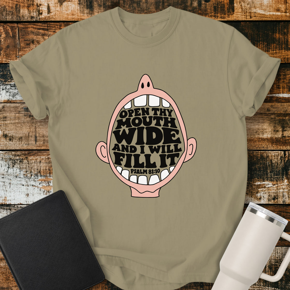 Khaki Christian T-shirt featuring a playful open-mouth illustration filled with the Scripture, “OPEN THY MOUTH WIDE AND I WILL FILL IT,” with the Bible reference “PSALM 81:10.”