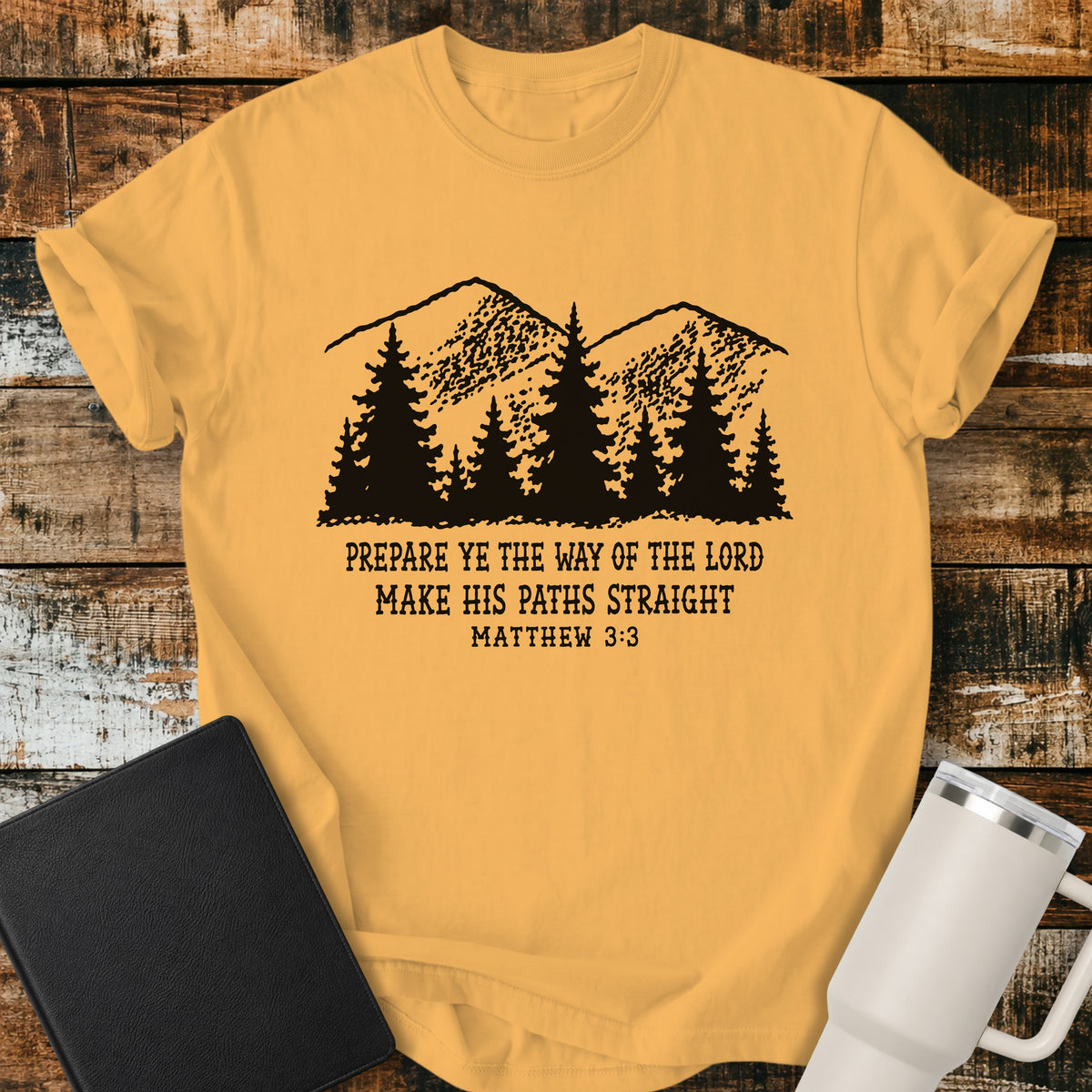 citrus yellow Christian t-shirt featuring a vintage mountain and pine forest illustration with the words “Prepare Ye the Way of the Lord, Make His Paths Straight” and Matthew 3:3. A rugged, outdoors-inspired biblical design with classic black typography.