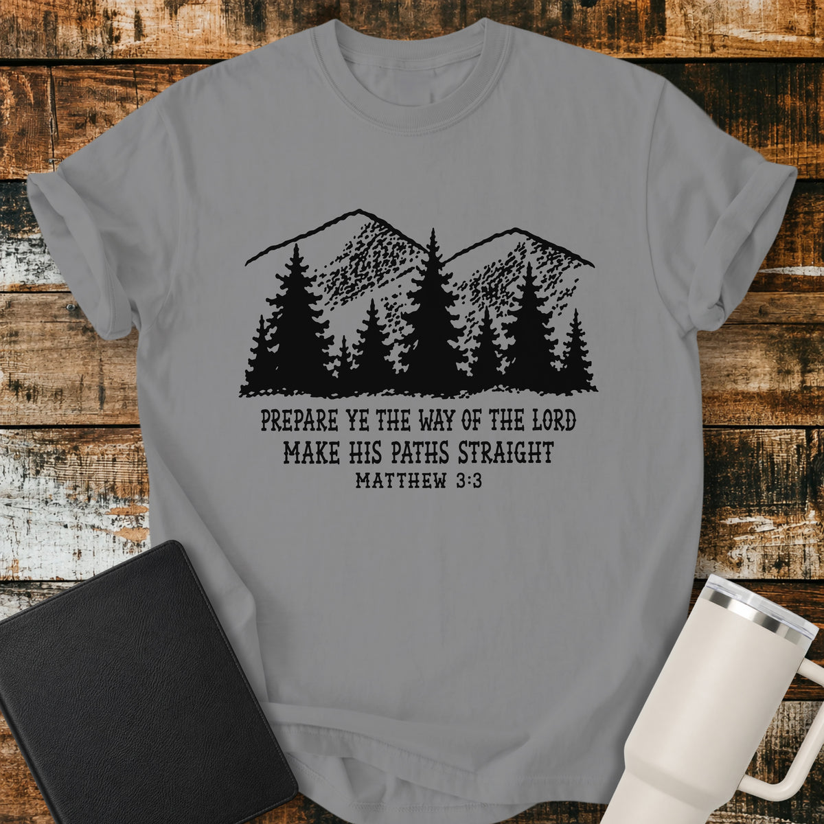 grey Christian t-shirt featuring a vintage mountain and pine forest illustration with the words “Prepare Ye the Way of the Lord, Make His Paths Straight” and Matthew 3:3. A rugged, outdoors-inspired biblical design with classic black typography.