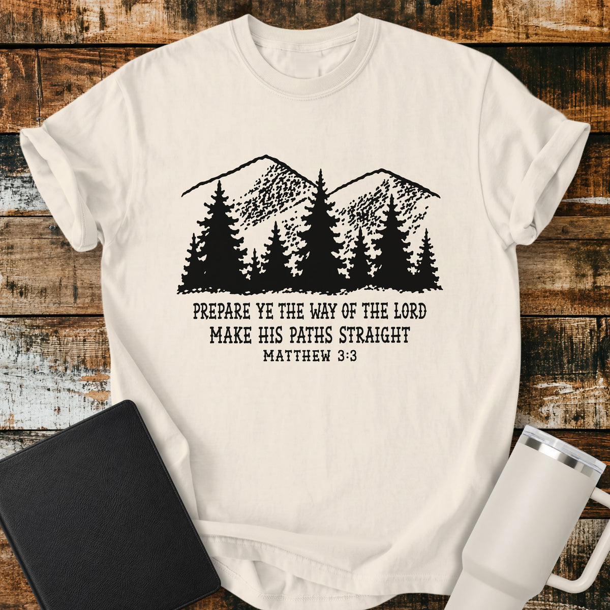 ivory Christian t-shirt featuring a vintage mountain and pine forest illustration with the words “Prepare Ye the Way of the Lord, Make His Paths Straight” and Matthew 3:3. A rugged, outdoors-inspired biblical design with classic black typography.