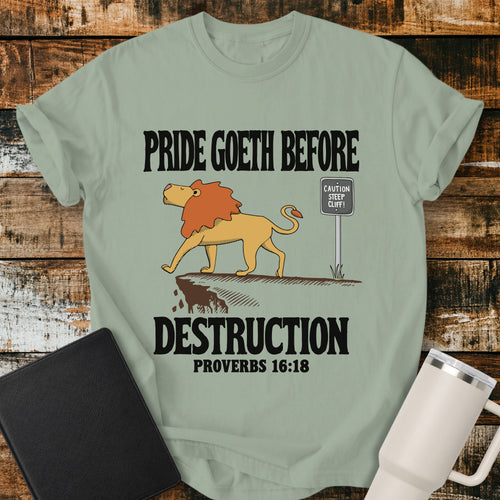 bay green Christian t-shirt featuring a lion confidently approaching a steep cliff, with bold vintage lettering reading “Pride Goeth Before Destruction” and Proverbs 16:18.
