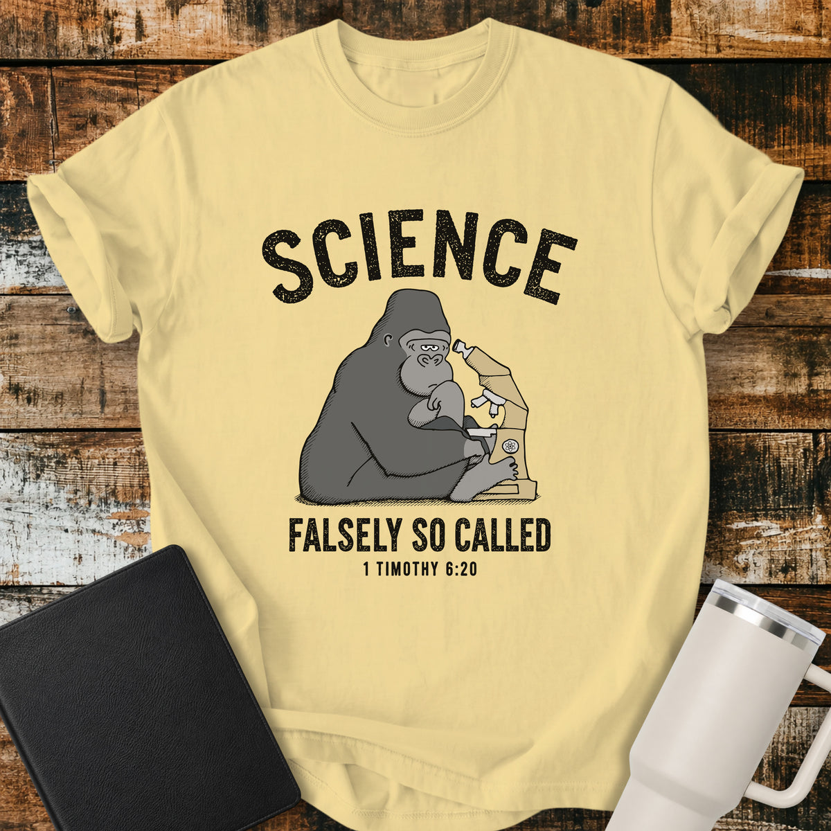 butter yellow Christian t-shirt featuring a gorilla examining a microscope beneath the word “Science,” with “Falsely So Called” and 1 Timothy 6:20 below. A clever retro-inspired biblical design referencing the KJV warning against “oppositions of science falsely so called.”