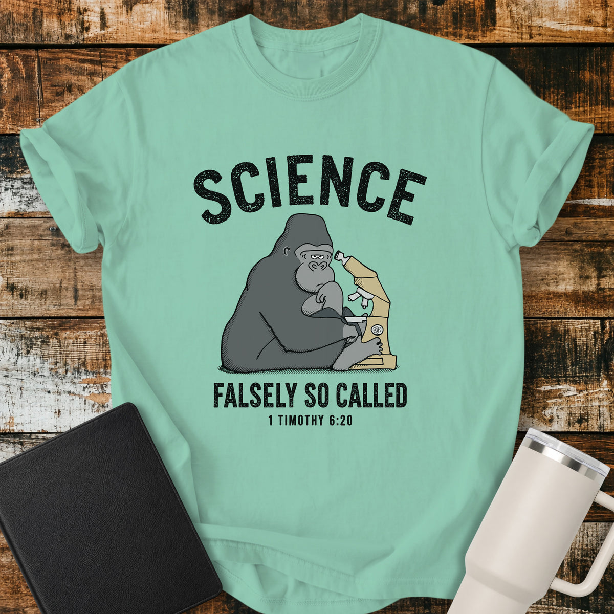 island reef green Christian t-shirt featuring a gorilla examining a microscope beneath the word “Science,” with “Falsely So Called” and 1 Timothy 6:20 below. A clever retro-inspired biblical design referencing the KJV warning against “oppositions of science falsely so called.”