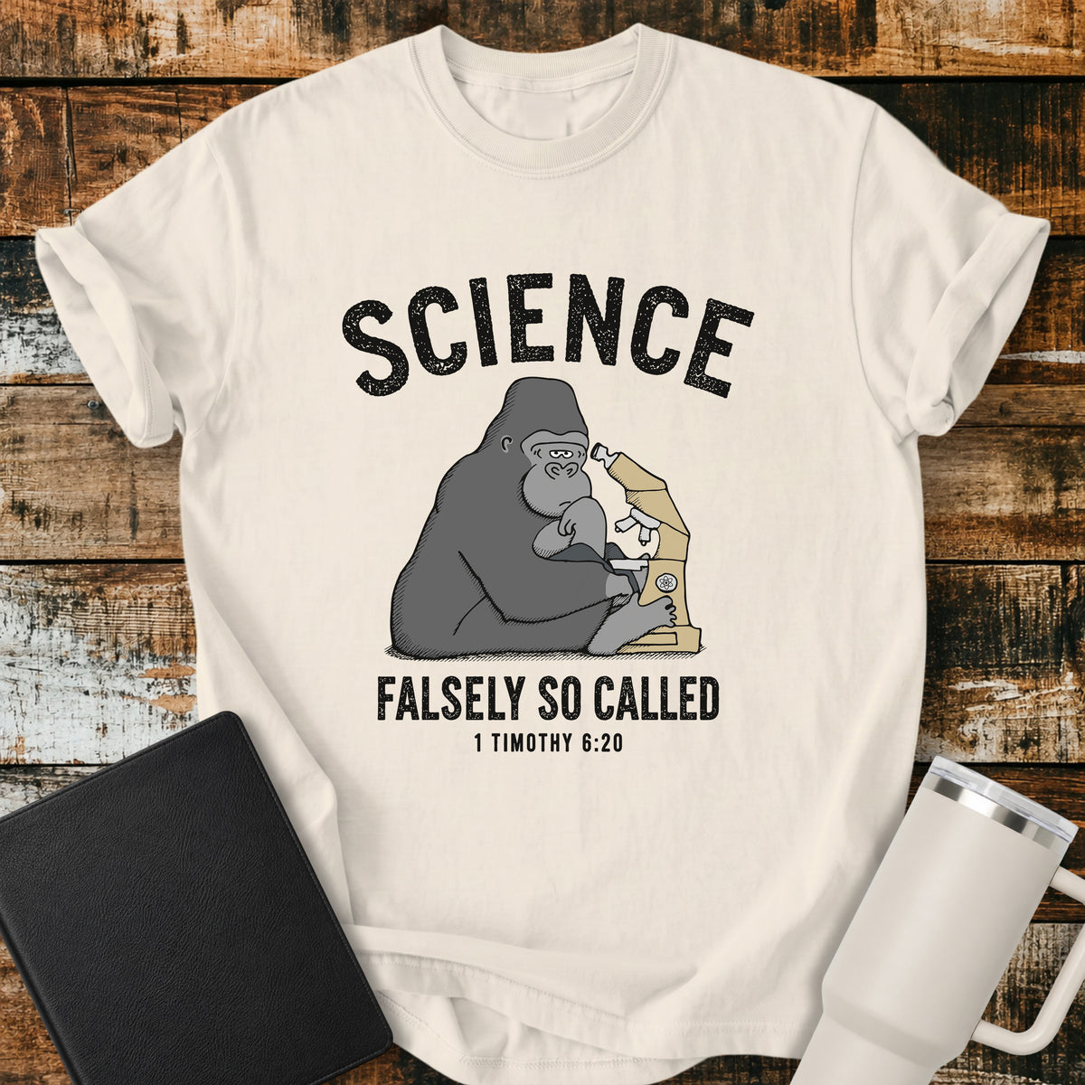 Ivory Christian t-shirt featuring a gorilla examining a microscope beneath the word “Science,” with “Falsely So Called” and 1 Timothy 6:20 below. A clever retro-inspired biblical design referencing the KJV warning against “oppositions of science falsely so called.”