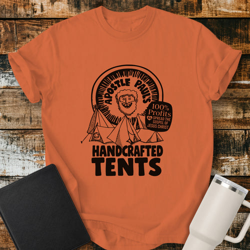 Burnt orange Christian T-shirt featuring Apostle Paul with handcrafted tents and the words “100% Profits to Spread the Gospel of Jesus Christ.”