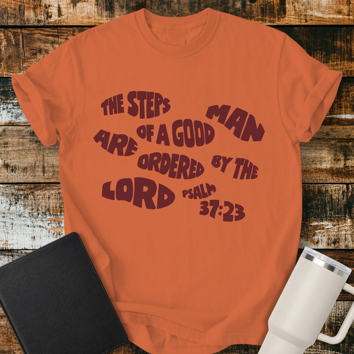 burnt orange Christian t-shirt featuring bold retro typography with Psalm 37:23: “The steps of a good man are ordered by the LORD.”