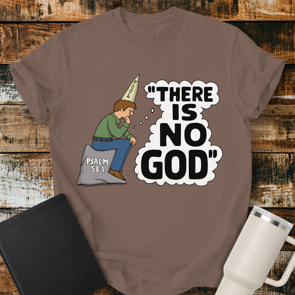 Espresso brown Christian t-shirt featuring a humorous illustration of a man in a “FOOL” cap pondering the statement “There Is No God,” inspired by Psalm 53:1.