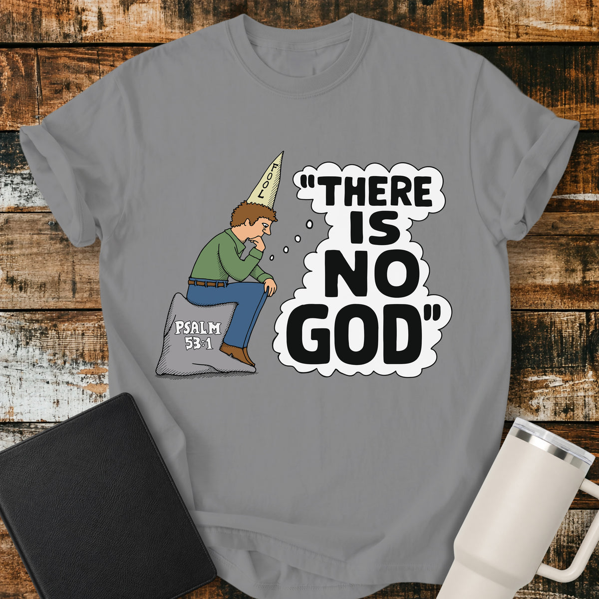 grey Christian t-shirt featuring a humorous illustration of a man in a “FOOL” cap pondering the statement “There Is No God,” inspired by Psalm 53:1.