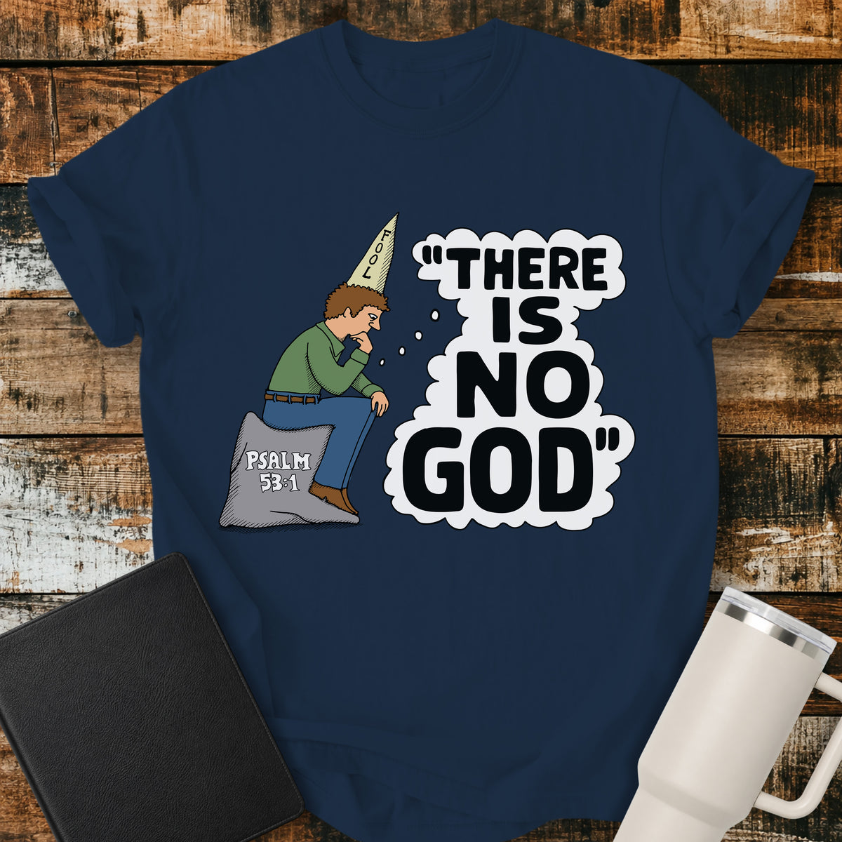 true navy blue Christian t-shirt featuring a humorous illustration of a man in a “FOOL” cap pondering the statement “There Is No God,” inspired by Psalm 53:1.