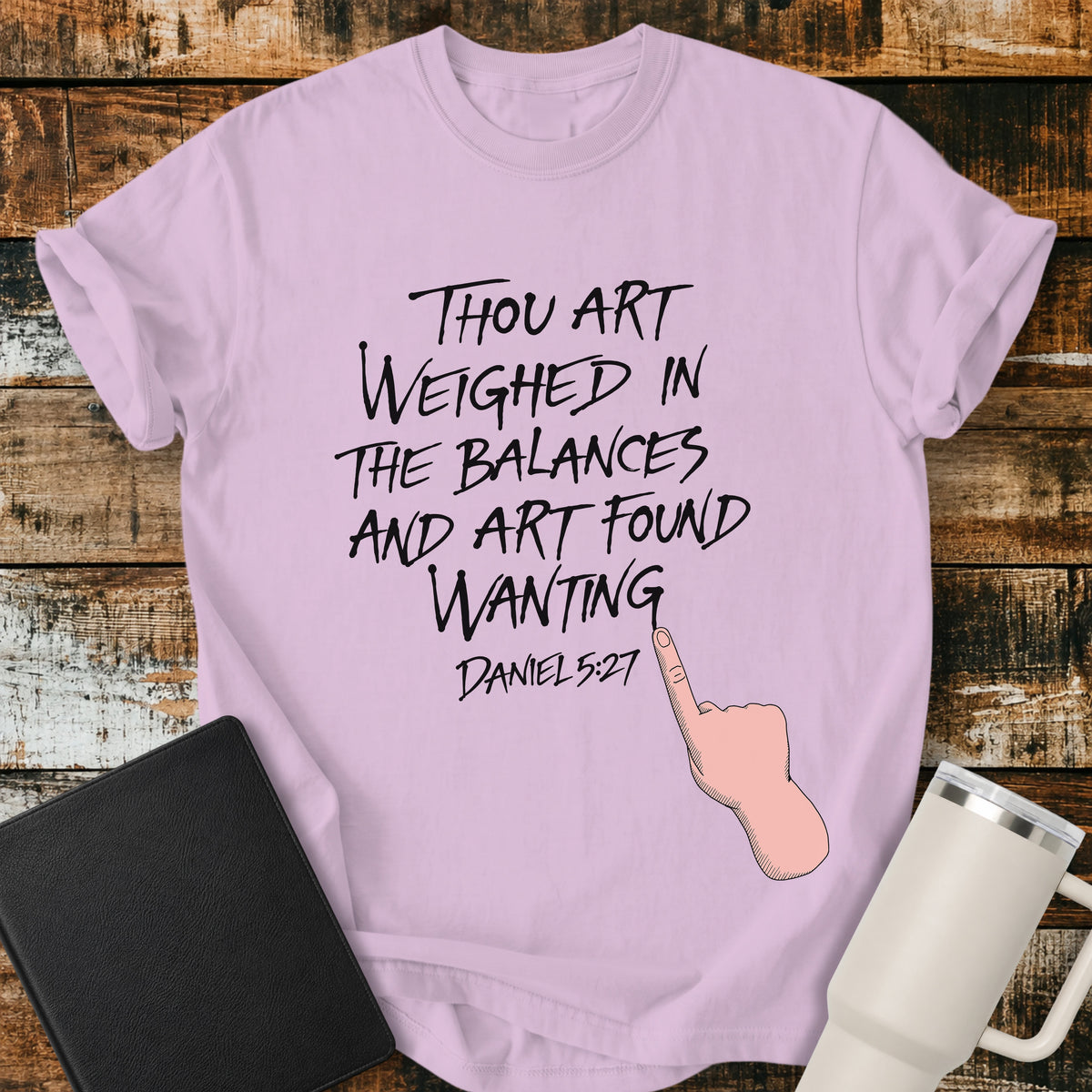 orchid purple Christian t-shirt featuring hand-lettered typography with Daniel 5:27: “Thou art weighed in the balances, and art found wanting,” paired with a pointing-hand illustration.