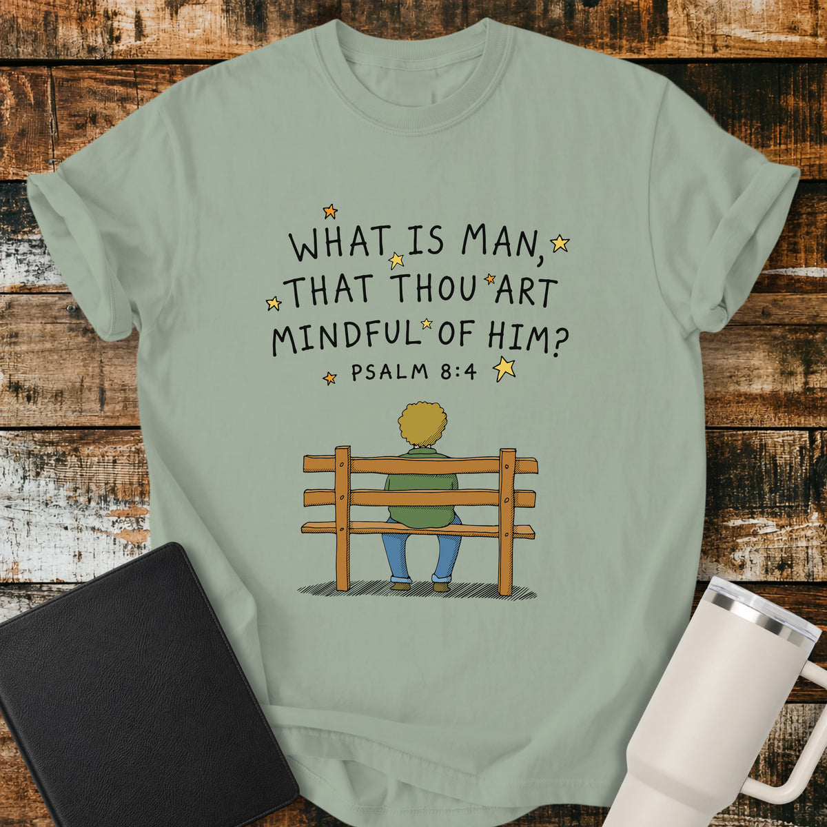 bay green Christian t-shirt featuring the words “What Is Man, That Thou Art Mindful of Him?” from Psalm 8:4, surrounded by simple stars above a person sitting quietly on a wooden bench. A reflective, vintage-inspired biblical design centered on God’s care for mankind.