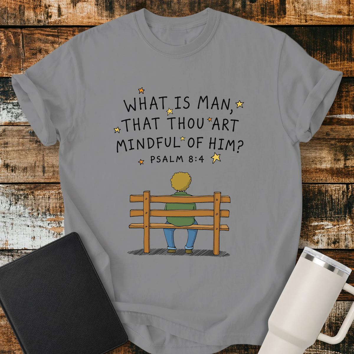 grey Christian t-shirt featuring the words “What Is Man, That Thou Art Mindful of Him?” from Psalm 8:4, surrounded by simple stars above a person sitting quietly on a wooden bench. A reflective, vintage-inspired biblical design centered on God’s care for mankind.